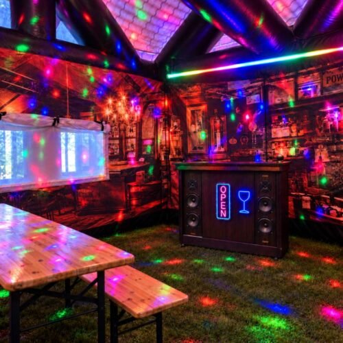 Full Party Package inside an inflatable pub, with wooden tables, benches, a Jukebox Bar and colourful lighting